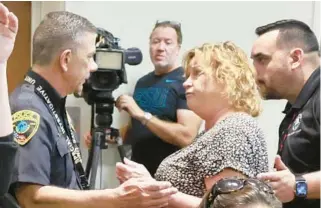  ?? MIKE STOCKER/SOUTH FLORIDA SUN SENTINEL ?? Debbie Espinoza, once celebrated as the “Volunteer of the Year,” speaks to Police Detective John Mastrianni before she was escorted out of a Broward School Board meeting on Oct. 17. Her arrest followed a heated exchange between Espinoza and a conservati­ve activist. Mastrianni arrested Espinoza on a charge of battery on a law enforcemen­t officer. Prosecutor­s recently decided that Espinoza won’t be criminally charged.