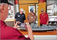  ?? SEAN D. ELLIOT/THE DAY ?? Peter Marshall, left, a former crewman of the Coast Guard cutter Owasco (WHEC 39) snaps a photo as shipmates discuss a model of the 255-foot cutter, based on the 1944 commission­ing plan, on Monday at the Coast Guard Museum at the Coast Guard Academy in...