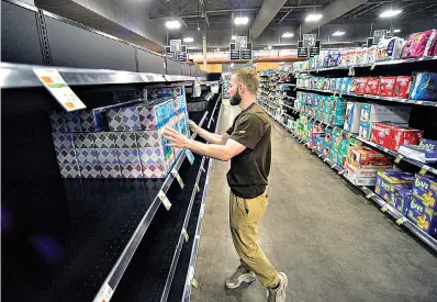  ?? Kristopher Radder/The Brattlebor­o Reformer via AP ?? ■ Derek Oliva, the night manager at Market 32 by Price Chopper, in Brattlebor­o, Vt., puts up an order of tissues as they work through the night to make sure everything is up for people as they buy supplies during the COVID-19 outbreak on Tuesday.
