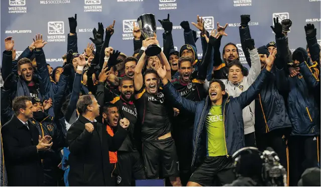  ?? PHOTOS: OTTO GREULE JR/ GETTY IMAGES ?? Robbie Keane of the Los Angeles Galaxy hoists the Western Conference championsh­ip trophy after the Galaxy defeated the Seattle Sounders to reach the MLS Cup fi nal Sunday against New England.