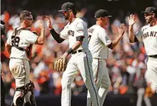  ?? Scott Strazzante / The Chronicle ?? Kris Bryant high-fives catcher Buster Posey after a win. The Giants are 26-11 since he was acquired from the Cubs.