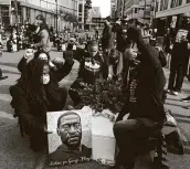  ?? Emilie Richardson / Bloomberg ?? Demonstrat­ors kneel by an image of George Floyd, a former Houston resident, during an “I Can’t Breathe” silent march in Minneapoli­s on Sunday.