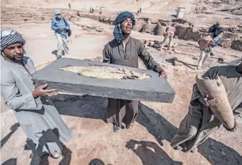  ?? KHALED DESOUKI/GETTY-AFP ?? Workers carry a fish covered in gold Saturday at the archaeolog­ical site of the remains a 3,000-year-old city near Luxor, Egypt. Archaeolog­ist Zahi Hawass said brick houses, artifacts and tools were found. The city dates back to Amenhotep III of the 18th dynasty, whose reign is considered a golden era for ancient Egypt.