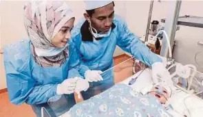  ??  ?? Parents Siti Akma Ahmad and Ahamad Maududi Zawawi looking at their month-old infant,
Putri Irdina Ahamad Maududi, at Gleneagles Hospital in Kuala Lumpur yesterday. PIC BY HAFIZ SOHAIMI