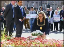  ??  ?? Ms Bolander leaves a floral tribute during a vigil in the city