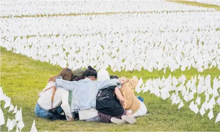  ?? PATRICK SEMANSKY/AP ?? Visitors sit among white flags Sept. 21 that are part of“In America: Remember”in Washington.