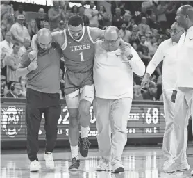  ?? JULIO CORTEZ/AP ?? Texas forward Dylan Disu is helped off the court by trainers during the second half of Monday night’s loss to Baylor in Waco.