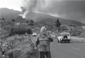  ?? EMILIO MORENATTI/AP ?? A resident takes a walk around his house Wednesday, near the erupting volcano, on the Canary island of La Palma, Spain. Officials say a volcano erupting for the past five weeks on the Spanish island is more active than ever. New lava flows have emerged following a partial collapse of the crater and threaten to engulf previously unaffected areas.