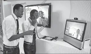  ?? LI LIANXING / CHINA DAILY ?? Two Africans try a visual phone at a recent exhibition in Rwanda.