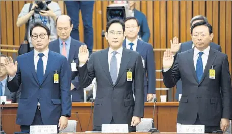  ?? Jung Yeon-je AFP/Getty Images ?? SK GROUP’S Chey Tae-won, left, Samsung Group’s Lee Jae-yong and Lotte Group’s Shin Dong-bin take an oath for the investigat­ion.