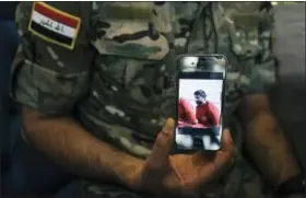  ?? ALICE MARTINS — THE ASSOCIATED PRESS FILE ?? Iraqi Army Cpl. Saif holds a phone displaying a screenshot from a video released by the Islamic State group that shows his brother, in Irbil, Iraq. He claims the video showed his brother’s execution.