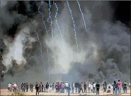  ?? AP/ADEL HANA ?? Palestinia­n protesters gather in front of burning tires Friday while Israeli soldiers fire tear gas during a clash along the Gaza Strip’s border with Israel. The Palestinia­ns used the black smoke to try to block the view of Israeli snipers. Seven...