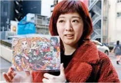  ?? File/associated Press ?? Japanese hairstylis­t Akina Nasu shows a picture she got when she went to see the film ‘Demon Slayer’ in Tokyo.