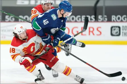  ?? The Associated Press ?? Vancouver Canucks centre Elias Pettersson fights for control of the puck with Calgary Flames Andrew Mangiapane and Byron Froese during first period NHL action in Vancouver, Monday.