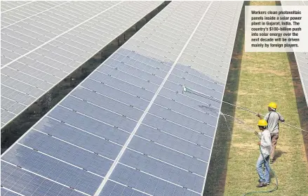  ??  ?? Workers clean photovolta­ic panels inside a solar power plant in Gujarat, India. The country’s $100- billion push into solar energy over the next decade will be driven mainly by foreign players.