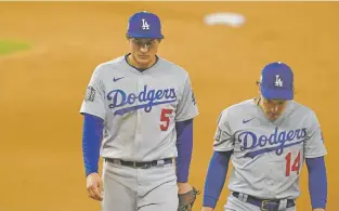  ?? ERIC GAY/ASSOCIATED PRESS ?? Dejected Dodgers shortstop Corey Seager, left, and Enrique Hernandez leave the field after Los Angeles lost to the Rays in Game 4 of the World Series on Saturday in Arlington, Texas. The Rays defeated the Dodgers 8-7 to tie the series at 2-2.