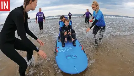  ?? ?? ■ Youngsters try surfing for the first time thanks to the specially adapted chair board