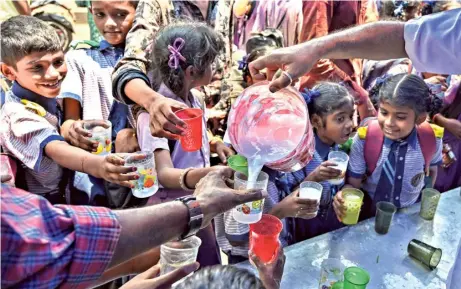  ?? K.R. DEEPAK ?? Mercury rising: Volunteers of Team Laddu, an NGO, o£ering buttermilk to schoolchil­dren and passers-by at the One Town area as temperatur­es soar in Visakhapat­nam on Tuesday.