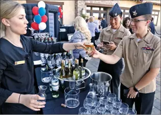 ?? Katharine Lotze/The Signal ?? Navy air controlman petty officer first class Crystal Money, right, gets a glass of wine from Emma Gonzalez at the Player’s Club Valencia for a wine tasting benefittin­g Operation Gratitude on Tuesday.