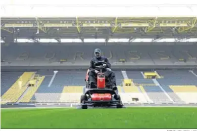  ?? FRIEDEMANN VOGEL / EFE ?? Un operario trabaja sobre el césped del Signal Iduna Park, estadio del Borussia Dortmund.