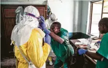  ?? Mark Naftalin / Associated Press ?? Health workers don protective clothing as they prepare to see patients suspected of having Ebola at Bikoro Hospital in Congo.