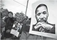  ?? REX PERRY / THE TENNESSEAN ?? Jessie Teasley, center in glasses, and Timothy Carroll, right, hold portraits of Martin Luther King Jr. as they march along Jefferson Street during the slain civil rights leader day Jan. 19, 1998.