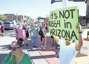  ?? MICHAEL CHOW/ARIZONA REPUBLIC ?? Demonstrat­ors hold signs against the 1864 near-total territoria­l abortion ban on Sunday while protesting in Scottsdale, Ariz.