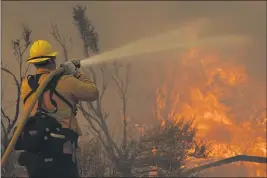  ?? MARCIO JOSE SANCHEZ — THE ASSOCIATED PRESS ?? Jesse Vasquez of the San Bernardino County Fire Department hoses down hot spots from the Bobcat wildfire on Saturday in Valyermo.