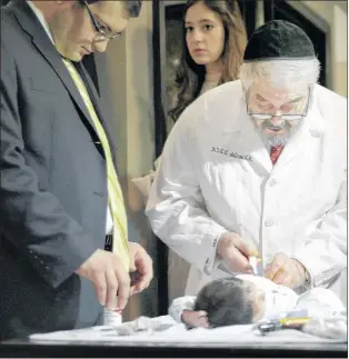  ?? AP FILE ?? A campaign to ban circumcisi­on for infants and children has taken hold in Iceland and Denmark but is far too radical a notion for Canada to consider, say observers here. Abraham Romi Cohn, right, examines Yosef Sananas before performing his bris, or...