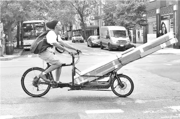  ??  ?? A person drives a cargo bike with long packages down 2nd Avenue in New York City. New orders, production and employment all grew solidly compared to July, with contributi­ons from 16 of the 18 industries surveyed, and especially large gains from the six big industries, according to the Institute for Supply Management’s closely-watched survey. — Reuters photo