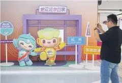  ?? AFP ?? A man takes photos of the 2022 Asian Games mascots in Hangzhou yesterday.