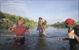  ?? AP photo ?? A man carries a little girl, who is clutching her Barbie doll, over the Rio Grande river toward Del Rio, Texas, early Wednesday as other migrants return to Ciudad Acuna, Mexico, some to avoid possible deportatio­n from the U.S. and others to load up with supplies.