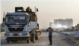  ?? — AP ?? A truck carries an earth-mover arrives at the constructi­on site of a highway in Ghaziabad on Saturday.