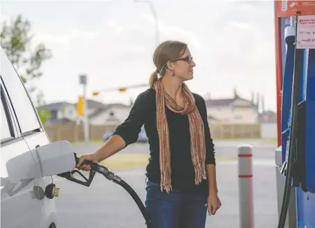  ?? AZIN GHAFFARI ?? Briana Trotter gases up at an Esso station in Calgary on Thursday. Prices for fuel are being forecast to fall in the city to 136.9 on Friday.