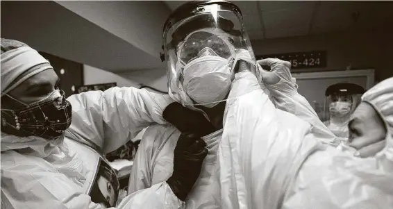  ?? Godofredo A. Vásquez / Staff photograph­er ?? Nurses help Dr. Joseph Varon get into the personal protective equipment required to enter the COVID-19 intensive care unit at United Memorial Medical Center.