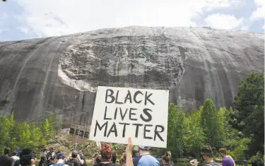  ?? Jessica McGowan / Getty Images ?? Demonstrat­ors protest last month at a carved Confederat­e monument at Stone Mountain Park in Georgia.