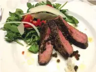  ?? Anne D’Innocenzio via AP ?? ■ This sliced Chianina T-bone with arugula, parmesan shavings and peppercorn­s was prepared by local Tuscan chef Ryan Hanley at Il Barattino, the villa in Cortona, Italy.