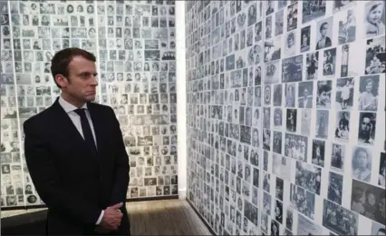  ?? PHILIPPE WOJAZER, THE ASSOCIATED PRESS ?? Independen­t centrist presidenti­al candidate Emmanuel Macron looks at some of the 2,500 photograph­s of young Jews deported from France.