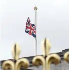  ?? John Phillips ?? > The Union flag flies at half mast above Buckingham Palace and (left) people lay flowers outside the palace gates