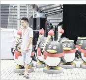  ??  ?? A man stands next to QQ mascots outside Tencent Holding’s new headquarte­rs in Shenzhen, China. Tencent has advanced to become China’s most valuable company.