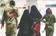  ?? DELIL SOULEIMAN / AFP / GETTY IMAGES FILES ?? An internal security patrol escorts women — reportedly wives of ISIL group fighters — in the al-Hol camp in al-Hasakeh governorat­e in northeaste­rn Syria in July.