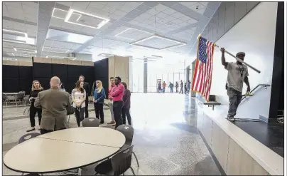  ?? Arkansas Democrat-Gazette/JOHN SYKES JR. ?? Custodian Corey Taylor returns an American flag to the cafetorium Tuesday as Principal Lance LeVar (back to camera) leads a tour of the new Robinson Middle School in west Little Rock. A ribbon-cutting ceremony was held Tuesday morning to celebrate completion of the school, part of the Pulaski County Special School District.