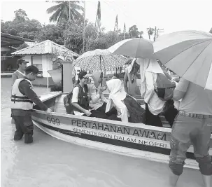  ??  ?? AKIBAT BANJIR: Anggota APM membantu menghantar calon peperiksaa­n UPSR ke SK Lingkungan.