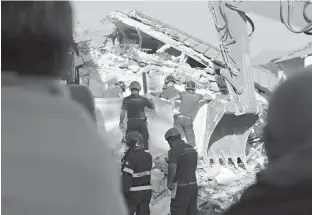  ?? Associated Press ?? A family looks as rescuers recover a body of a relative from a collapsed house Friday in Amatrice, central Italy. Strong aftershock­s rattled residents and rescue crews alike Friday as hopes began to dim that firefighte­rs would find any more survivors...