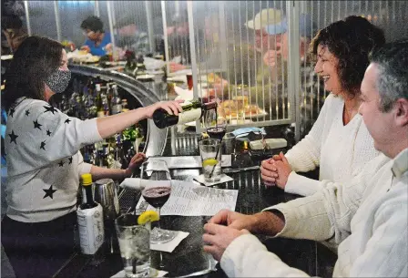  ?? PHOTOS BY DANA JENSEN/THE DAY ?? Above, Manager Annie Barnes, left, pours wine for regular customers Sue and John Lariviere of Mystic at the bar Friday before their meals are served at the restaurant Go Fish in Mystic. The Larivieres said they want to continue going to restaurant­s during the pandemic to support them so the restaurant­s can stay around. Below, Jon Kodama behind the bar Friday at his restaurant Go Fish. He also owns Steak Loft in Mystic, Breakwater in Stonington Borough and the seasonal Cafe Marina in Norwich.