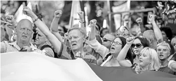  ??  ?? Protesters deploy a giant Polish national flag and shout slogans during a demonstrat­ion against a judicial reform pushed through by the right-wing government but criticised by the EU as a threat to judicial independen­ce in front of the Senate Building...