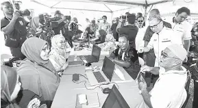  ?? — Gambar Bernama ?? SANTUNI RAKYAT: Fahmi (kanan) beramah mesra dengan penduduk setempat yang sedang mendaftar akaun dalam PADU pada Program Jiwa MADANI di Kampung Sungai Putat dekat Ayer Keroh di Melaka, semalam.