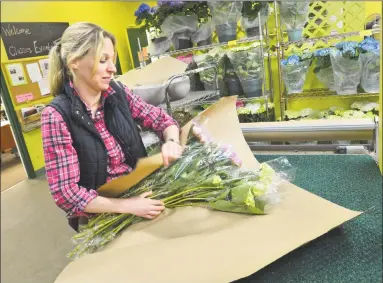  ?? Alex von Kleydorff / Hearst Connecticu­t Media ?? Marissa Groot wraps an order at East Coast Wholesale Flowers for a local florist on Tuesday in Norwalk during the busiest week of the year for the company, the week leading up to Mother’s Day. The staff was busy with shipments of flowers from all over...