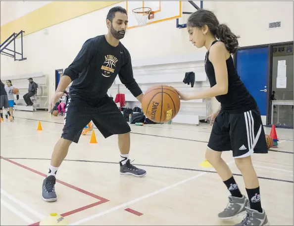  ?? GERRY KAHRMANN/PNG ?? Surinder Grewal gives a young basketball player a few tips at the AthElite Basketball Camp in Surrey.