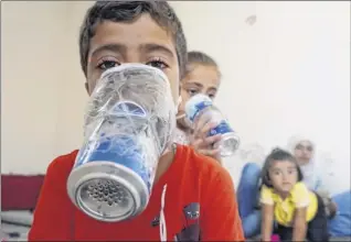  ?? Muhammad Haj Kadour / AFP / Getty Images ?? Children try improvised gas masks in their home in Binnish in Syria’s rebelheld northern Idlib province Wednesday as part of preparatio­ns for any upcoming raids.